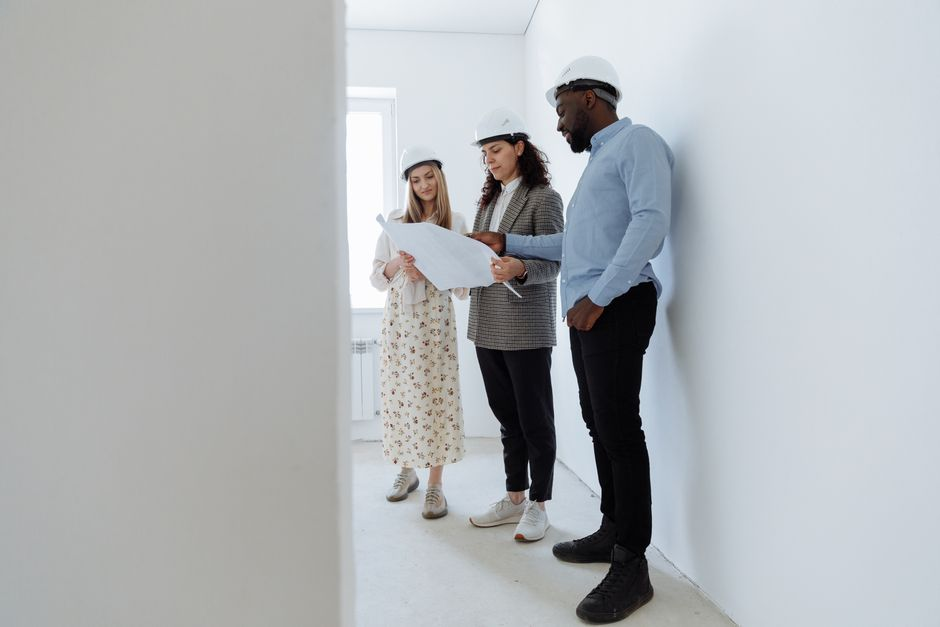 Homeowners seated at a table reviewing floor plans and discussing renovation options.