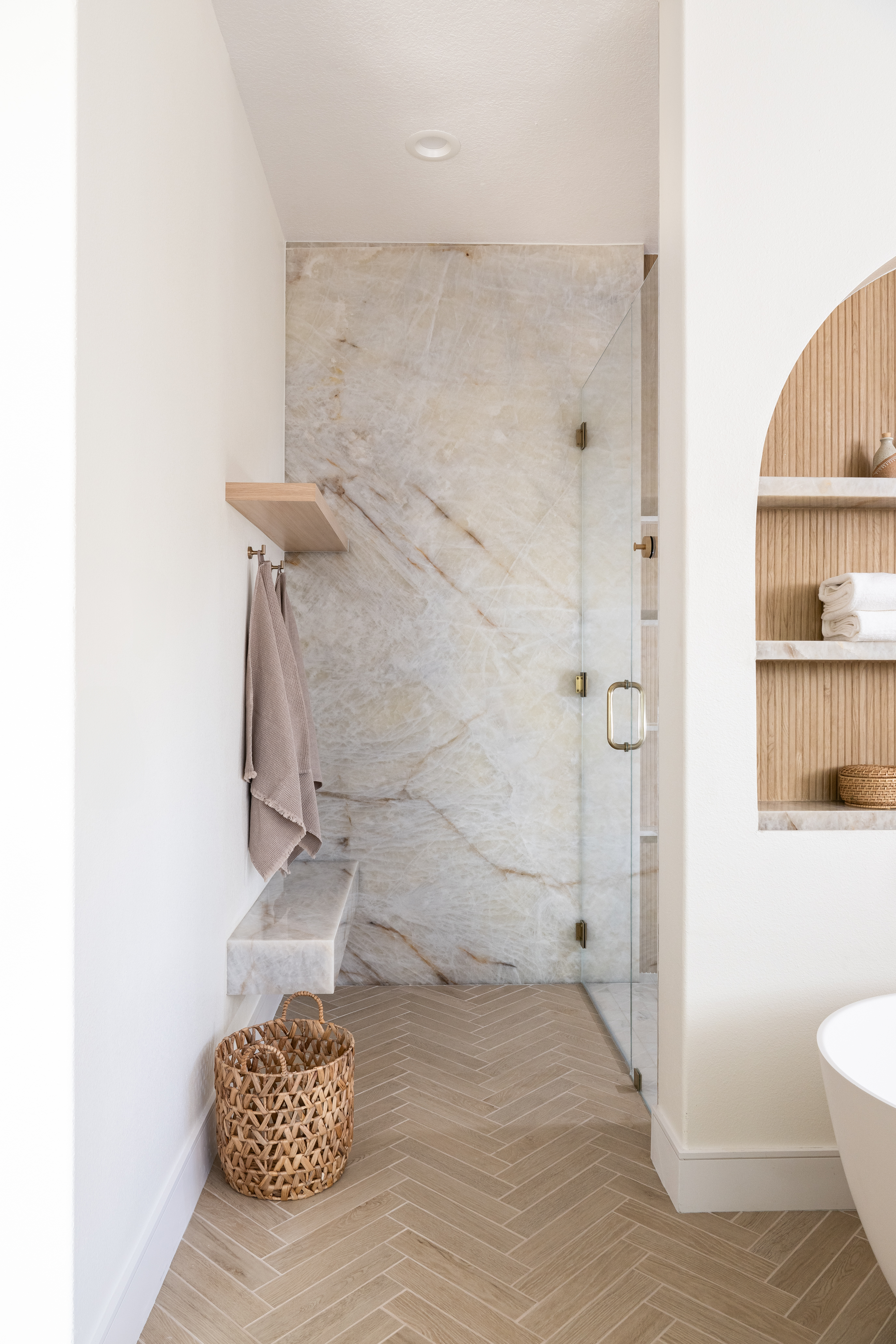 Modern walk-in shower with marble walls and herringbone floor